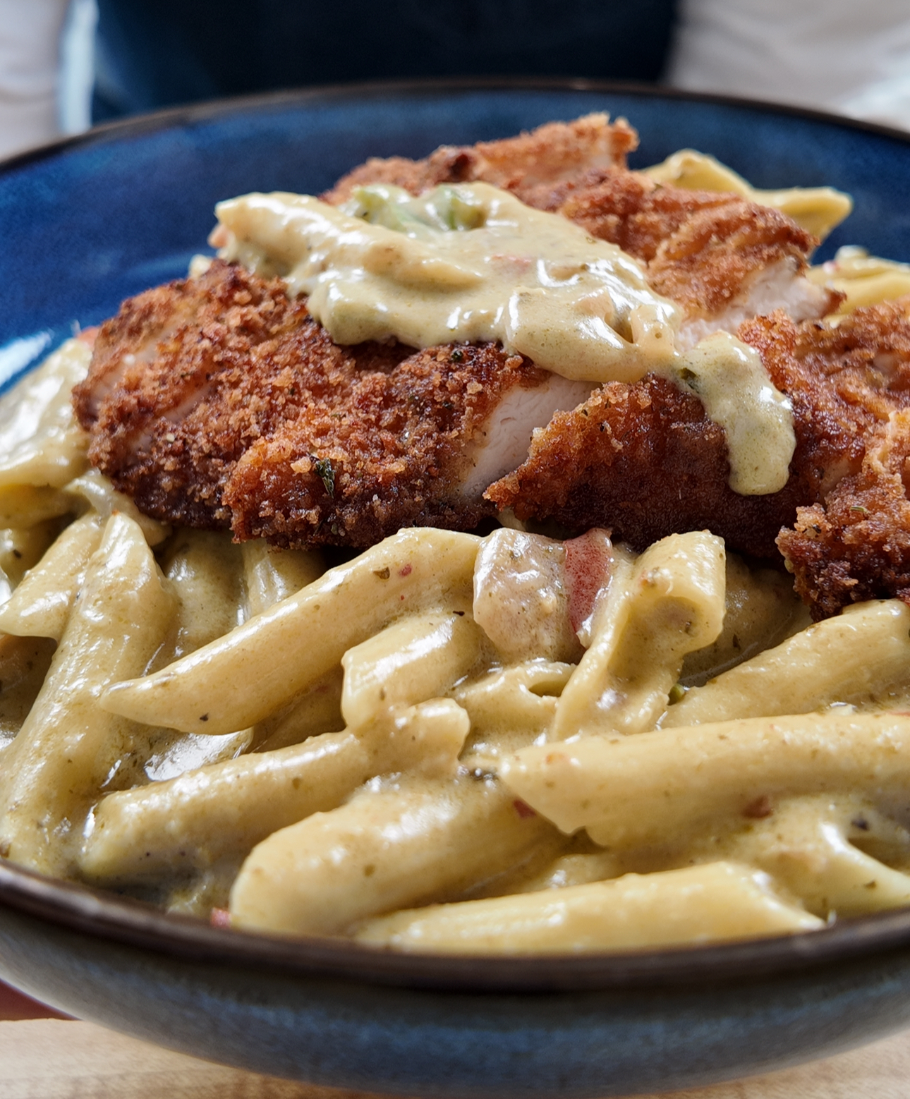 creamy penne pesto with crispy fried chicken in a blue bowl