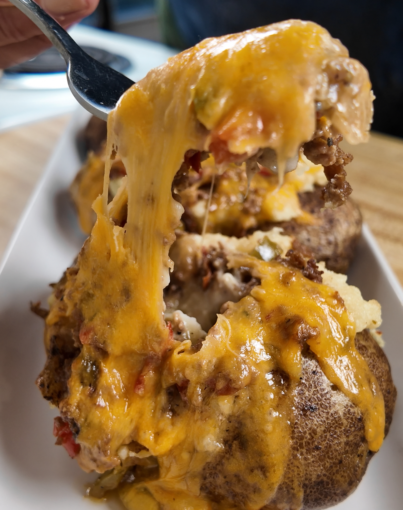 Loaded Philly cheesesteak baked potato with cheddar cheese