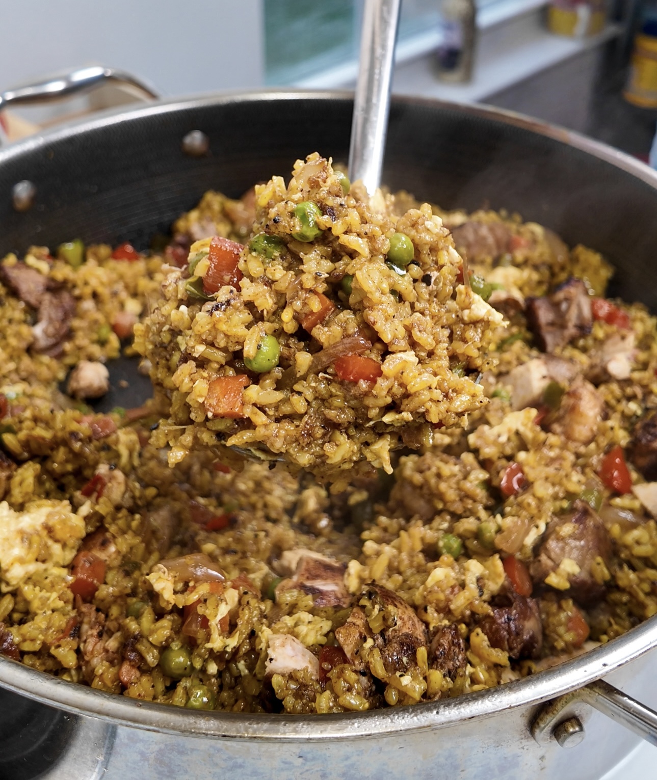 A spoonful of Jamaican Fried Rice in a large pan